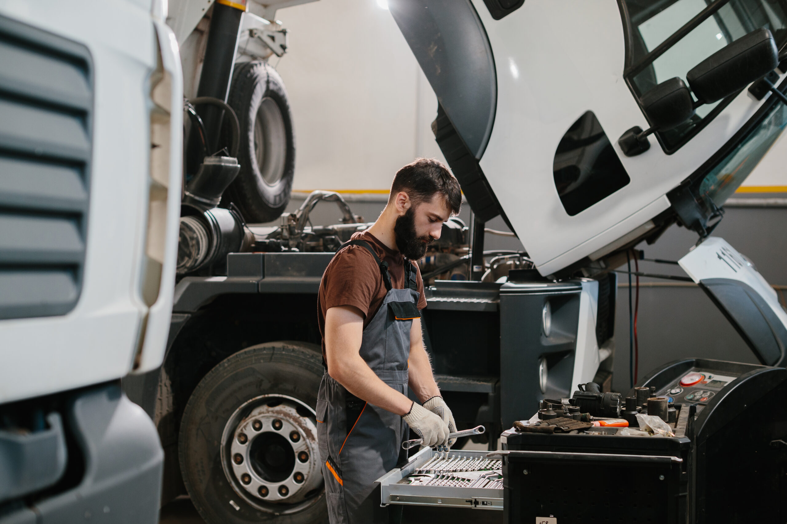 Professional auto mechanic choosing right wrench for repairing truck in garage